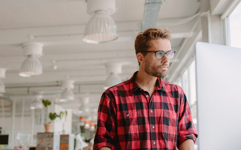 Ung man som arbetar på datorn på en modern arbetsplats