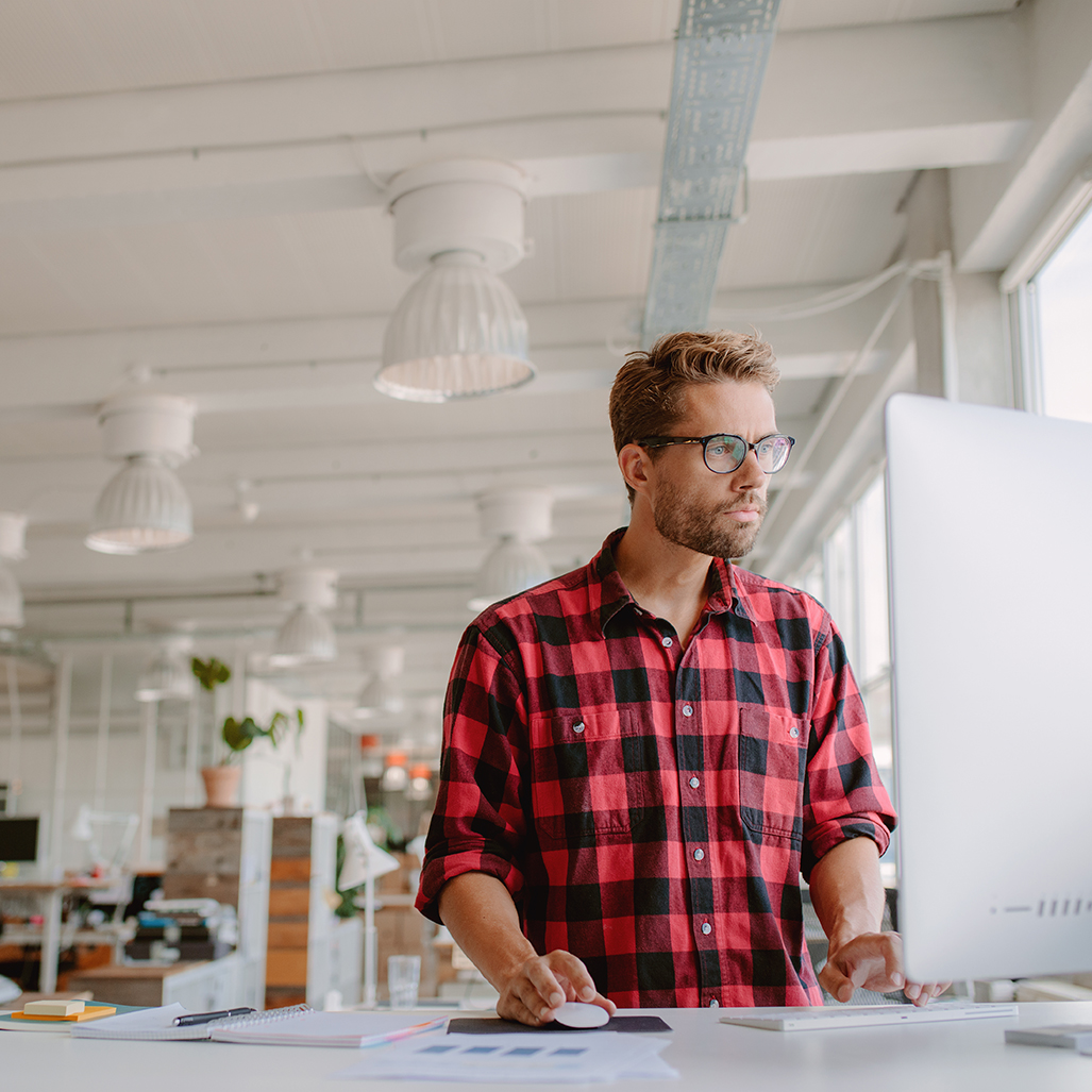 Ung man som arbetar på datorn på en modern arbetsplats